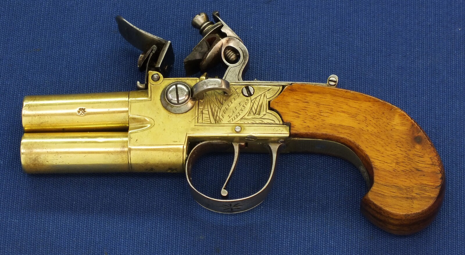 An antique English Brass Tap-Action Box-Lock double barreled Flintlock Pocket Pistol by Bullied(Bulleid) late Wilkinson Bristol circa 1800 with thumbpiece safety catch. Caliber 9,5mm, length 15,5cm. In very good condition. Price 850 euro